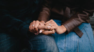 Two people holding hands sitting next to each other
